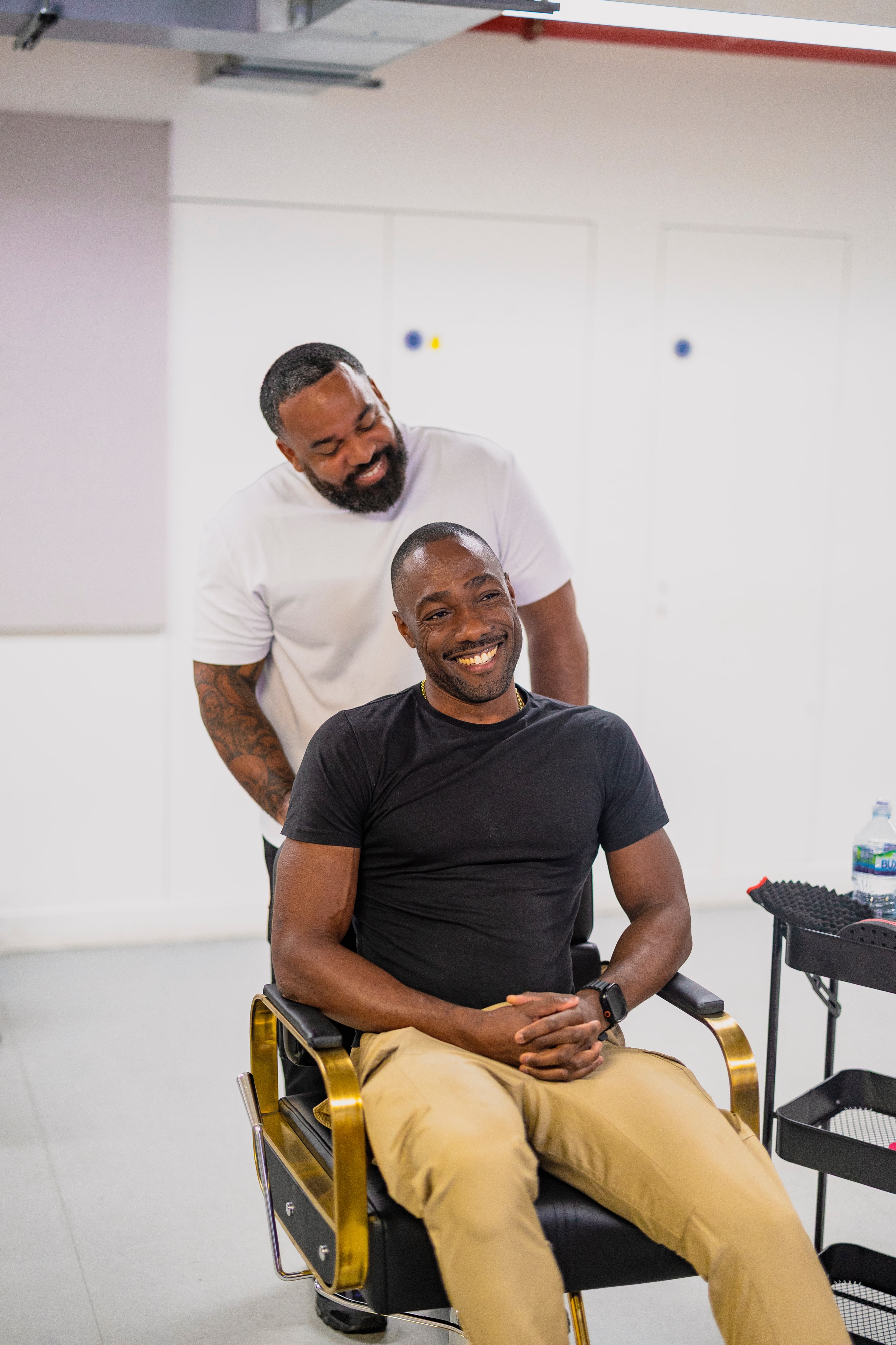 Two cast members in rehearsal — barbershop chair scene