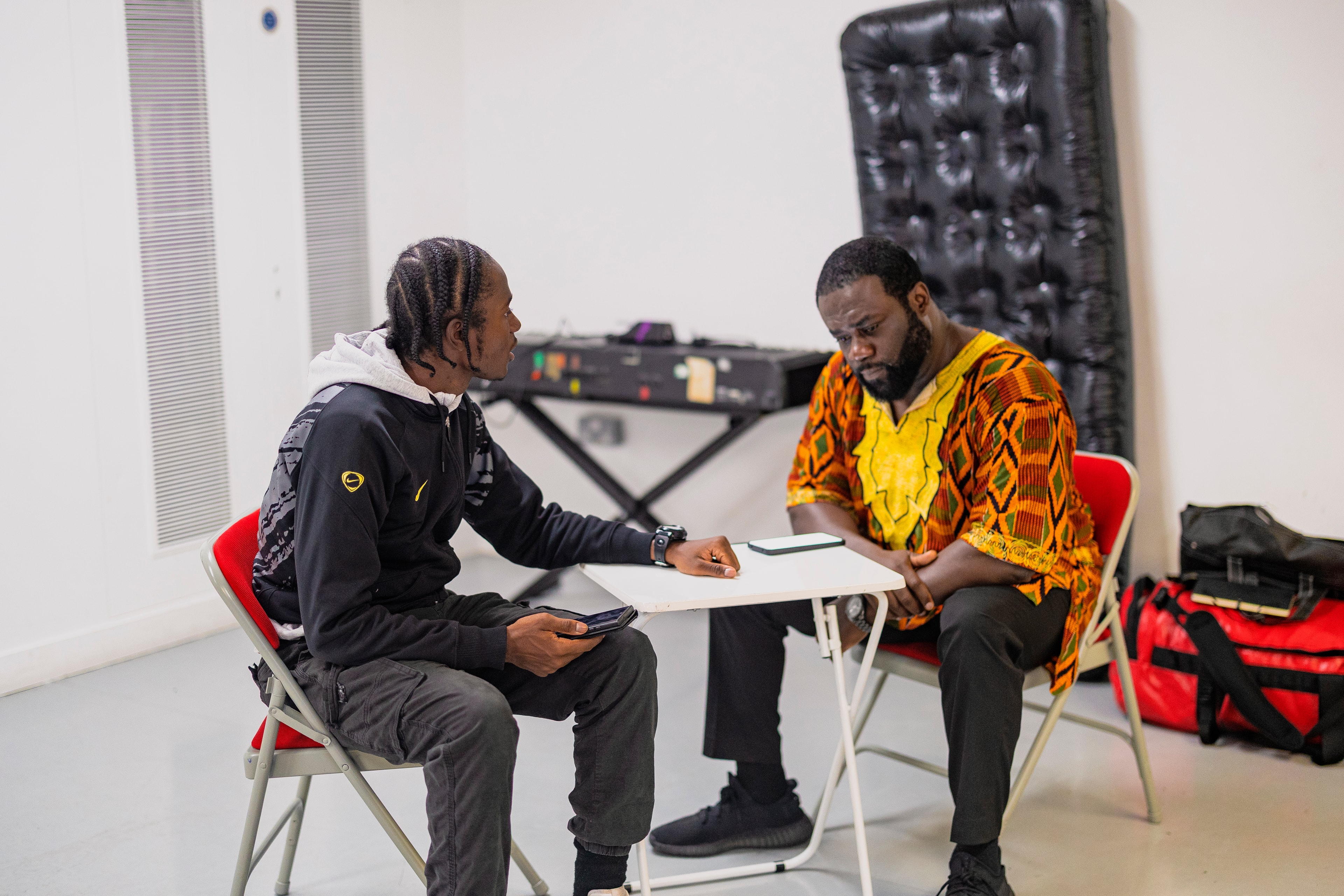 Two cast members in discussion at a rehearsal table